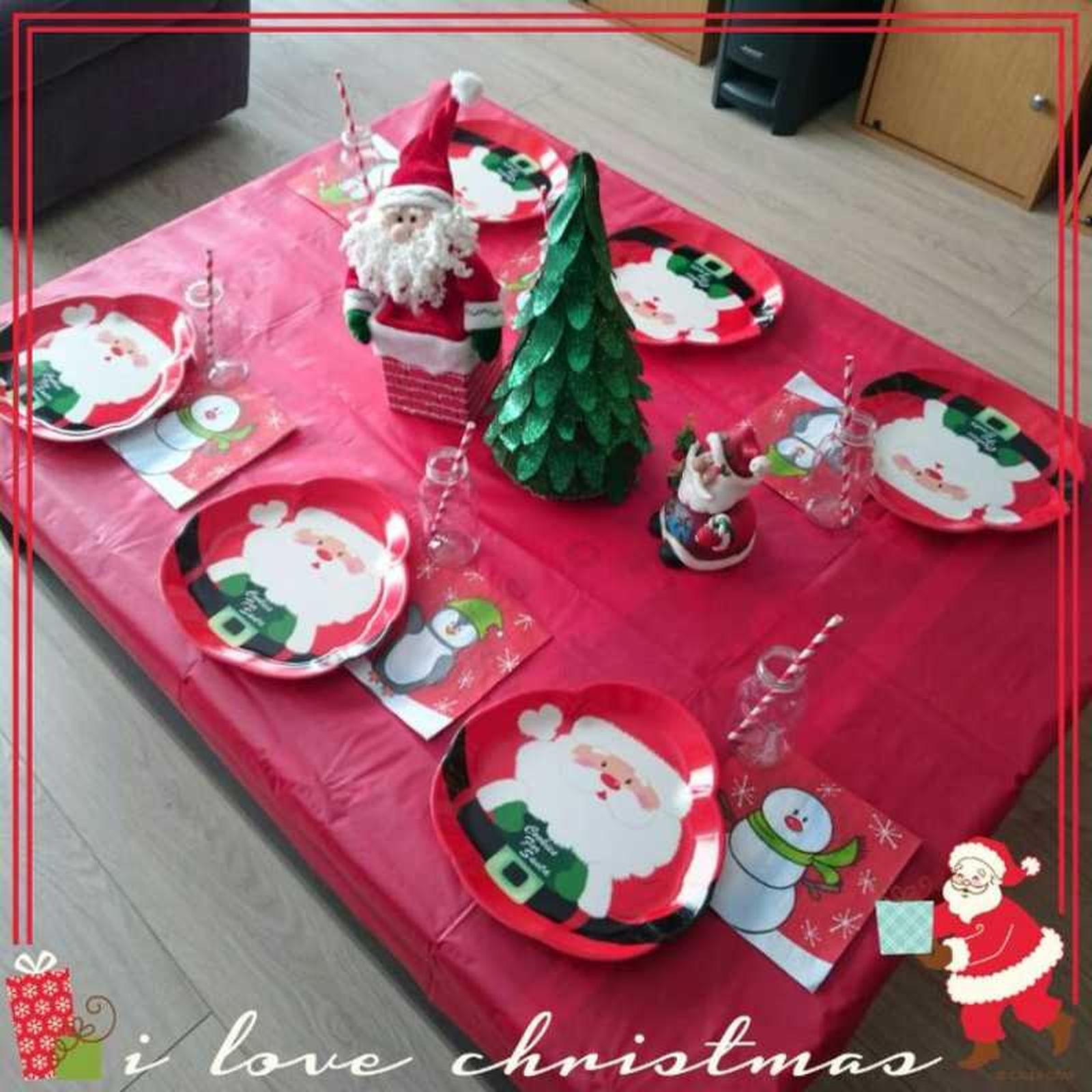 Mesa de Navidad decorada con mantel rojo y vajilla navideña infantil.