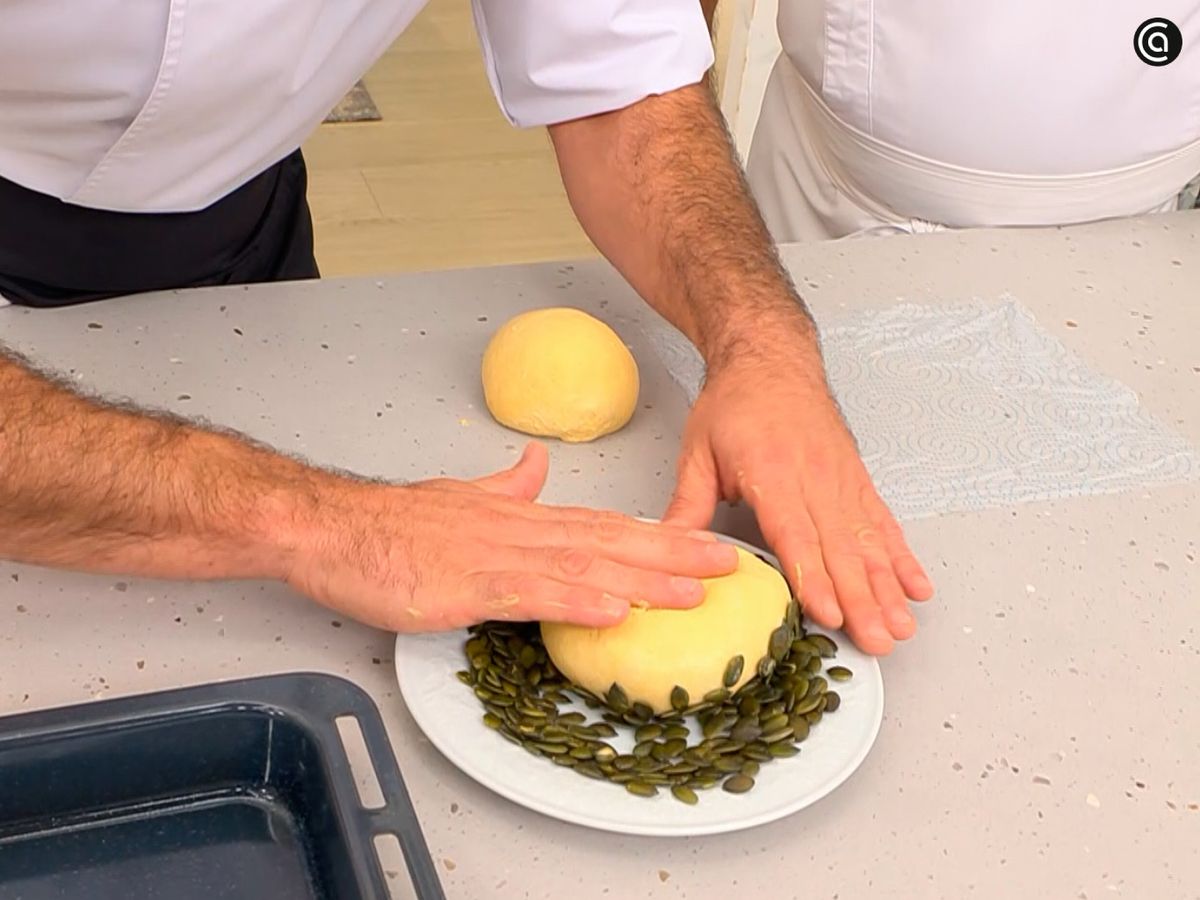 Divide la masa y cúbrela con pipas de calabaza