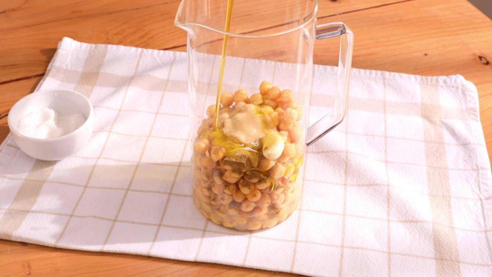 Incorpora el zumo de limón, ajo, comino, sal, tahina y aceite de oliva al vaso de la batidora Incorpora el zumo de limón, ajo, comino, sal, tahina y aceite de oliva al vaso de la batidora