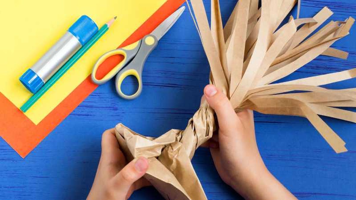 Segundo paso para hacer un árbol de cartón, retorcer la bolsa para hacer el tronco y la base.