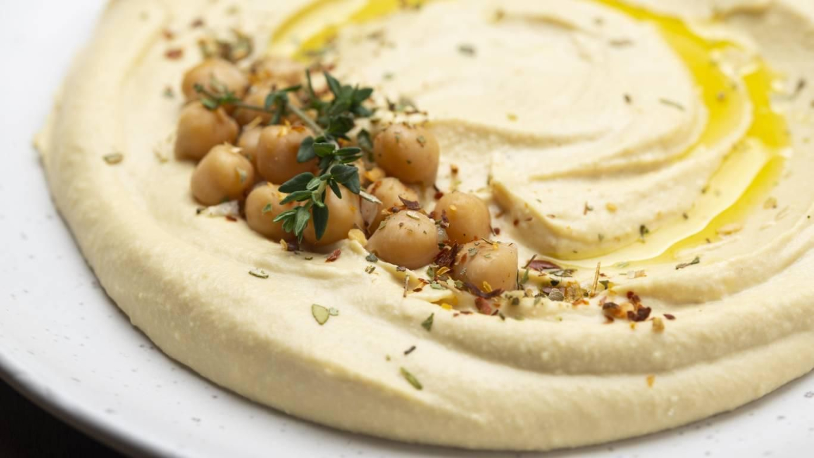 Hummus tradicional decorado con garbanzos y especias.