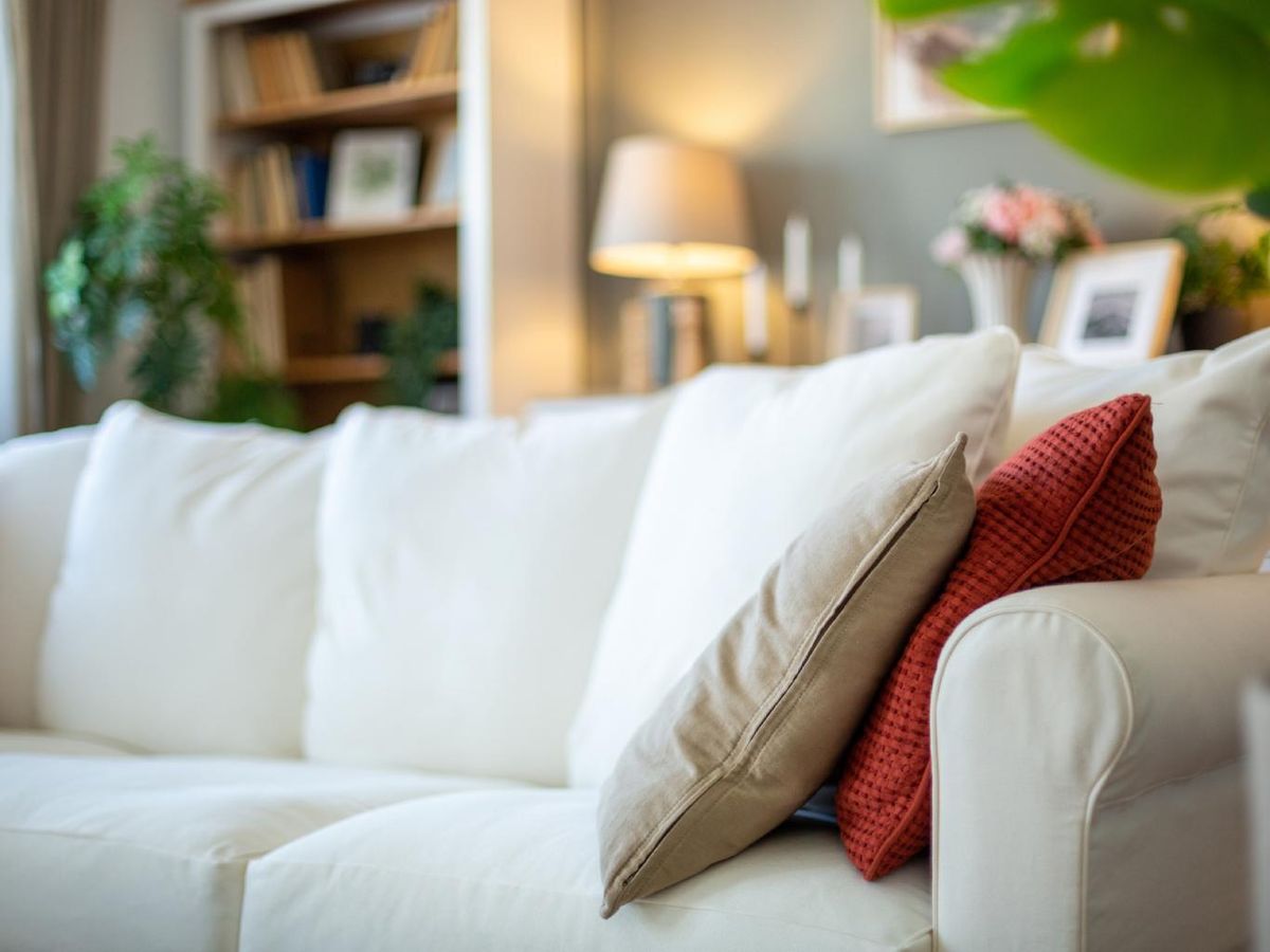 Sofá beige con un cojín rojo.