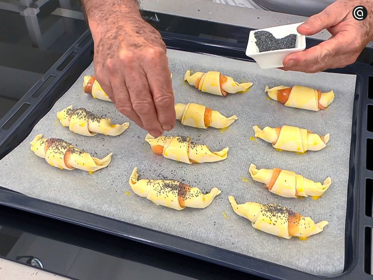 Pinta con huevo y espolvorea semillas sobre los mini cruasanes antes de hornearlos