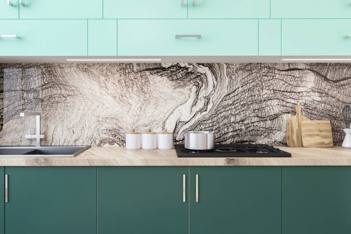 Cocina verde con papel pintado de efecto natural en el salpicadero.