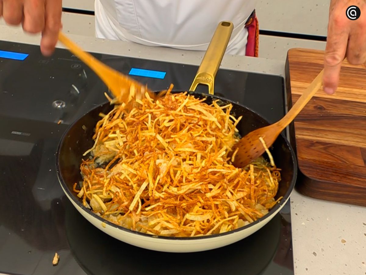 Añade a la sartén el bacalao desmigado y las patatas paja, y mezcla sin romperlas