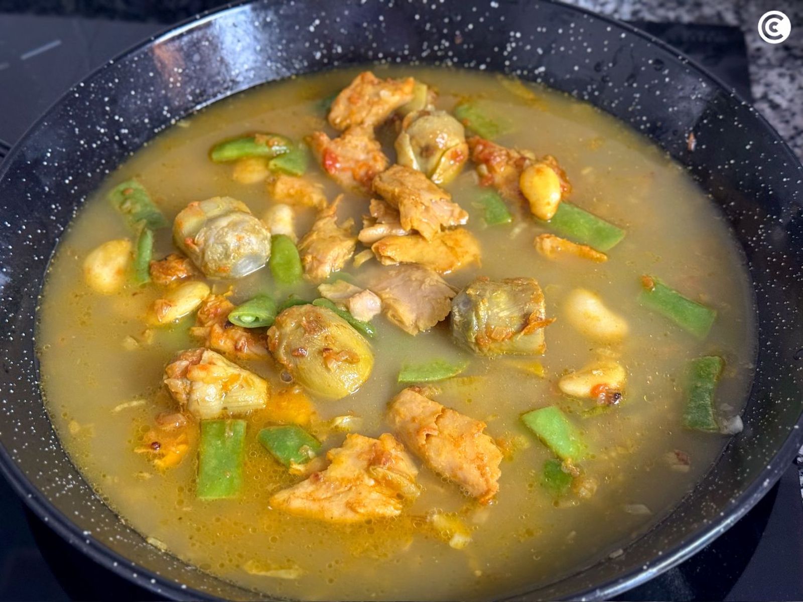 Agregar la mitad del caldo a la paella vegana Agregar la mitad del caldo a la paella vegana