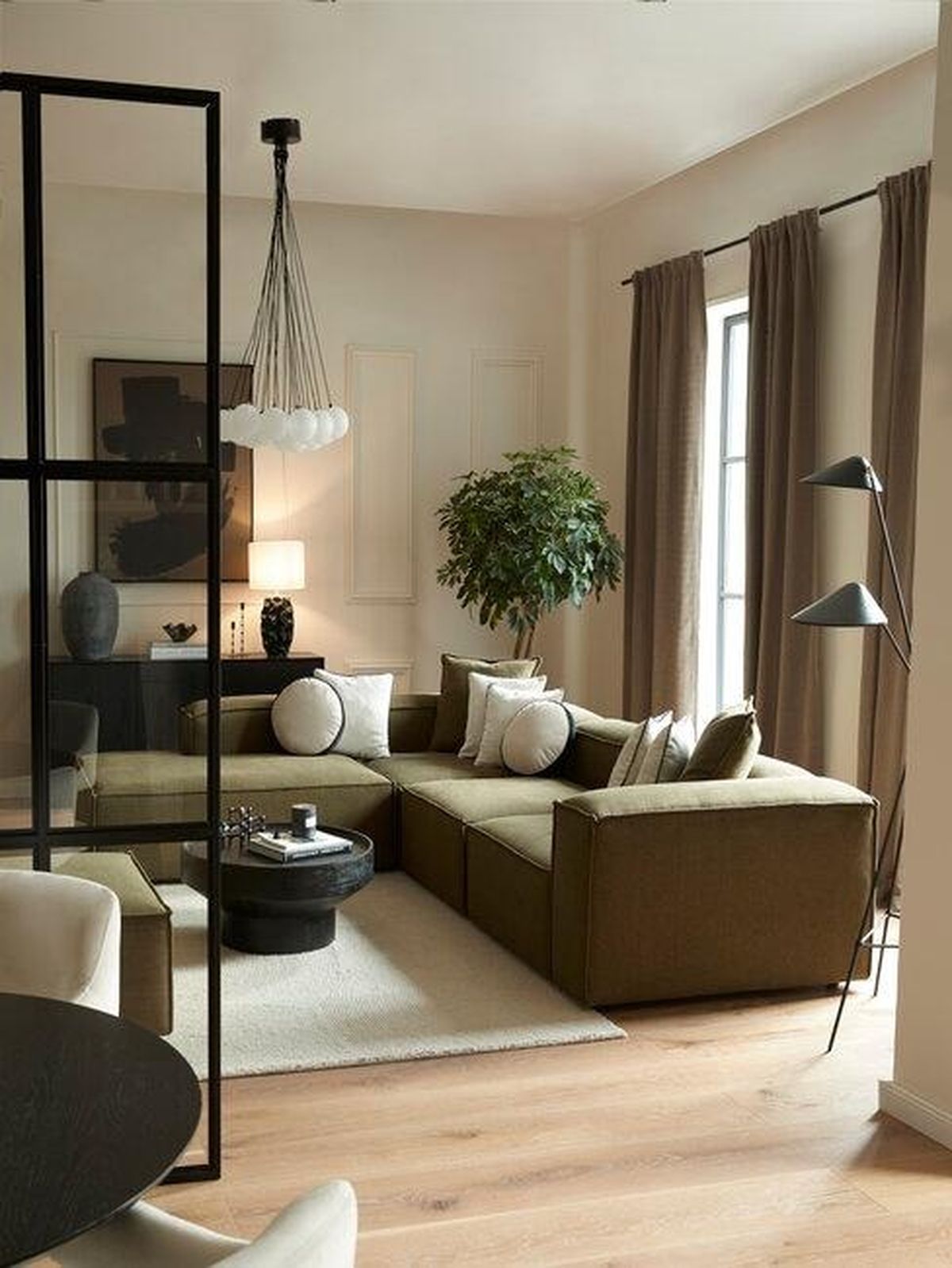 Salón moderno con sofá verde oliva y muebles oscuros.