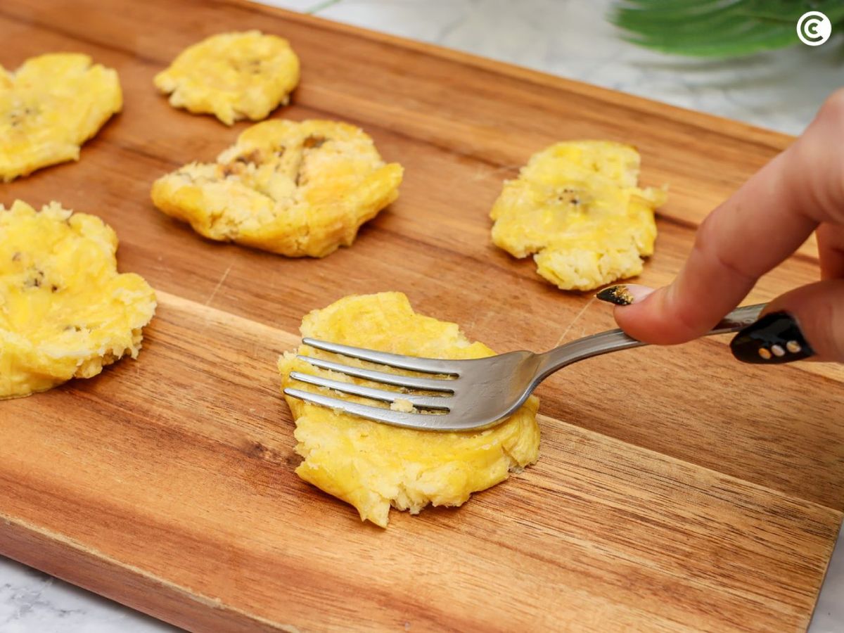 Aplastar el plátano macho frito para hacer los patacones