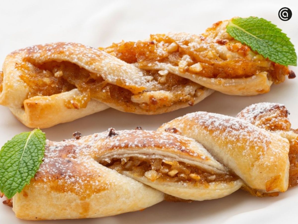 Trenzas de hojaldre rellenas de manzana caramelizada y frutos secos, doradas y crujientes, perfectas para acompañar un café o té caliente.