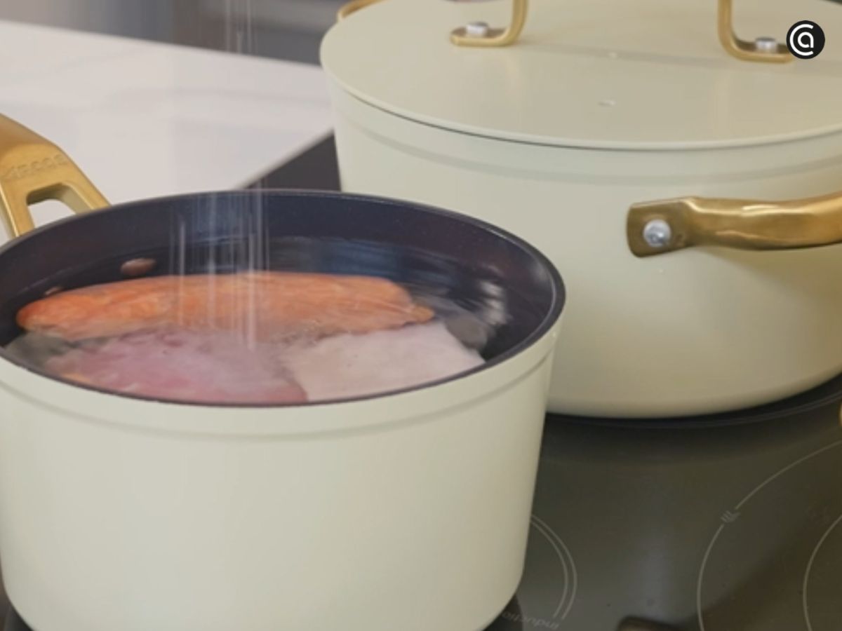 Cocción del chorizo y la panceta en una cazuela con agua y sal, la base del sabor del guiso.