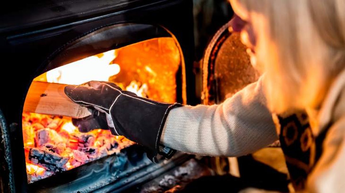 Mujer introduciendo leña en estufa de leña