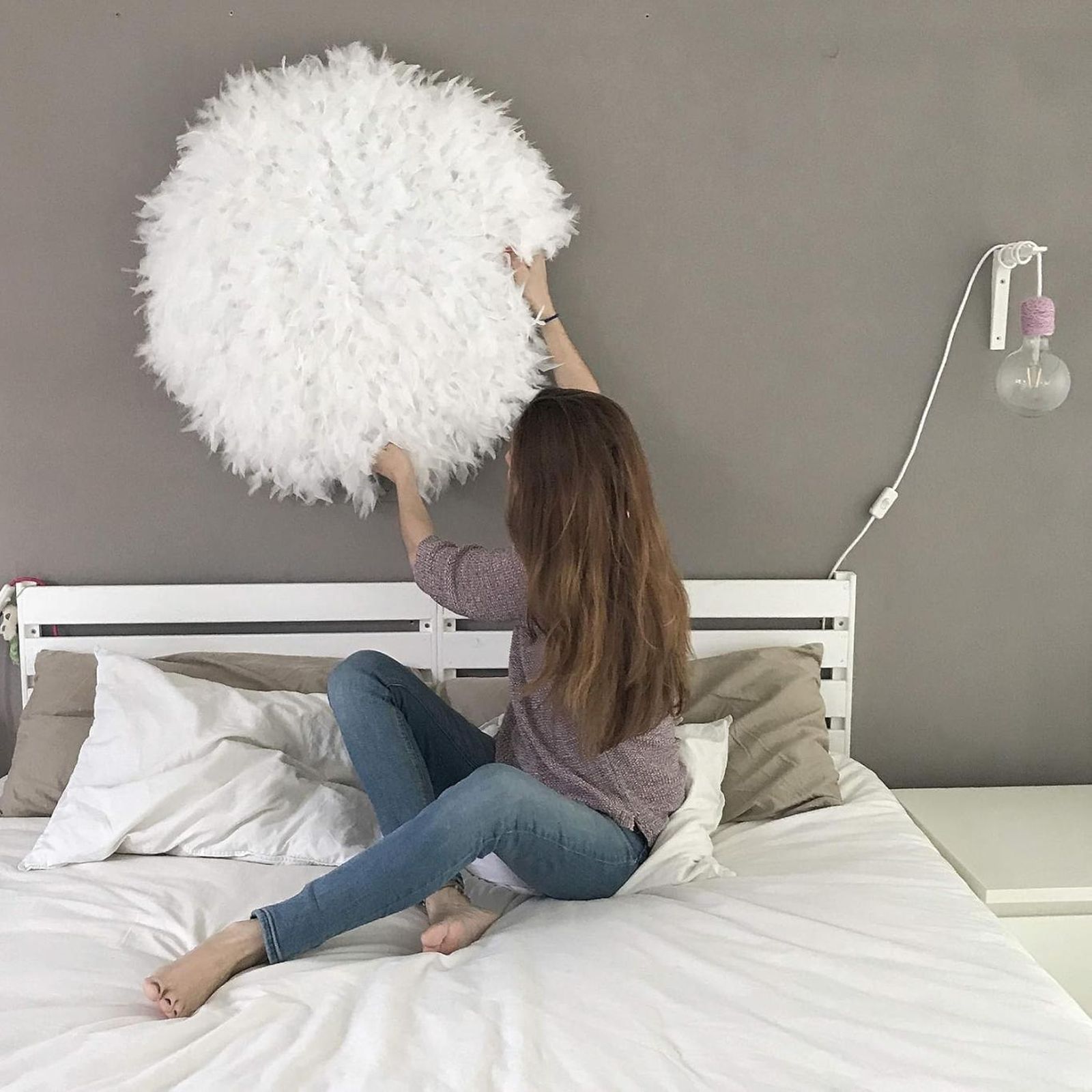 Mujer colocando un juju hat en la pared del dormitorio. Mujer colocando un juju hat en la pared del dormitorio.