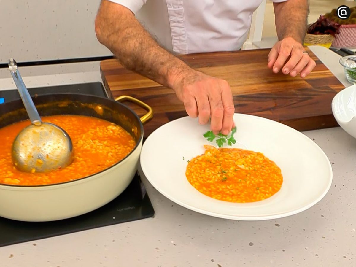 Espolvorea perejil picado sobre el arroz cremoso con gambas