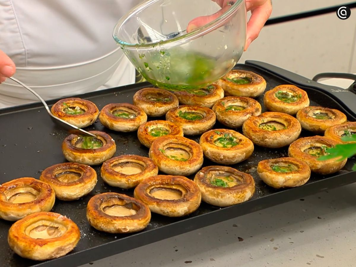 Añade el aceite de ajo y perejil a los sombreros de los champiñones