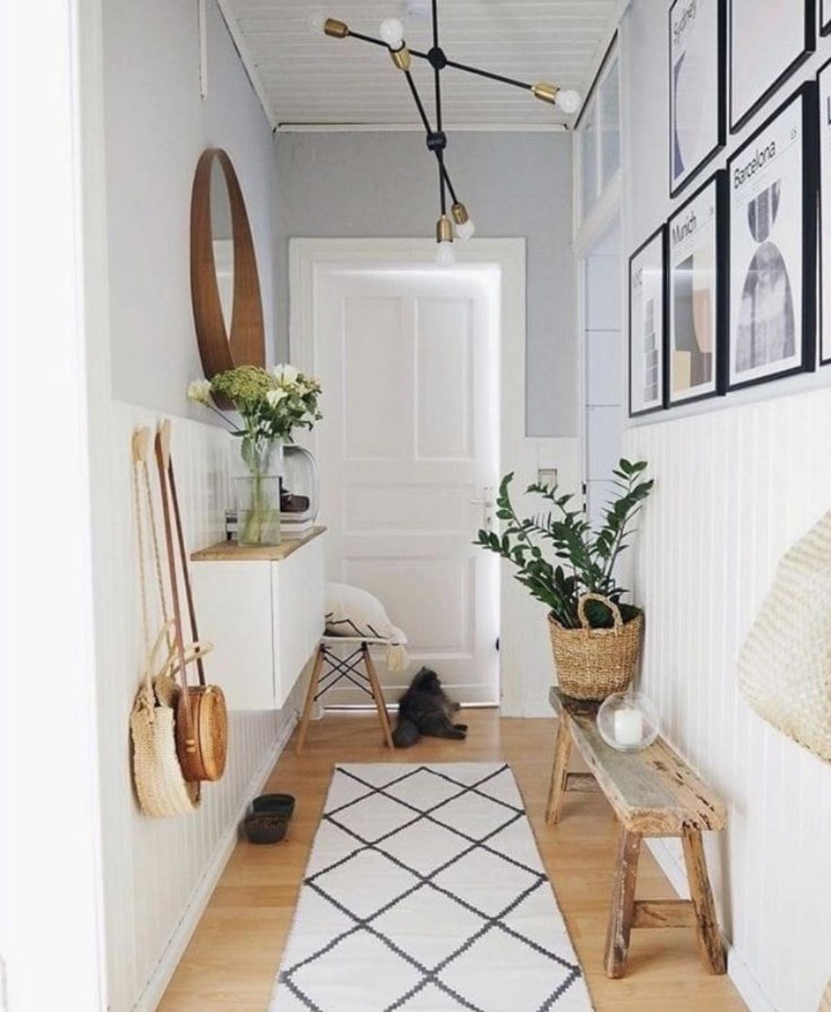 Pasillo con cuadros en la pared, alfombra y complementos decorativos.