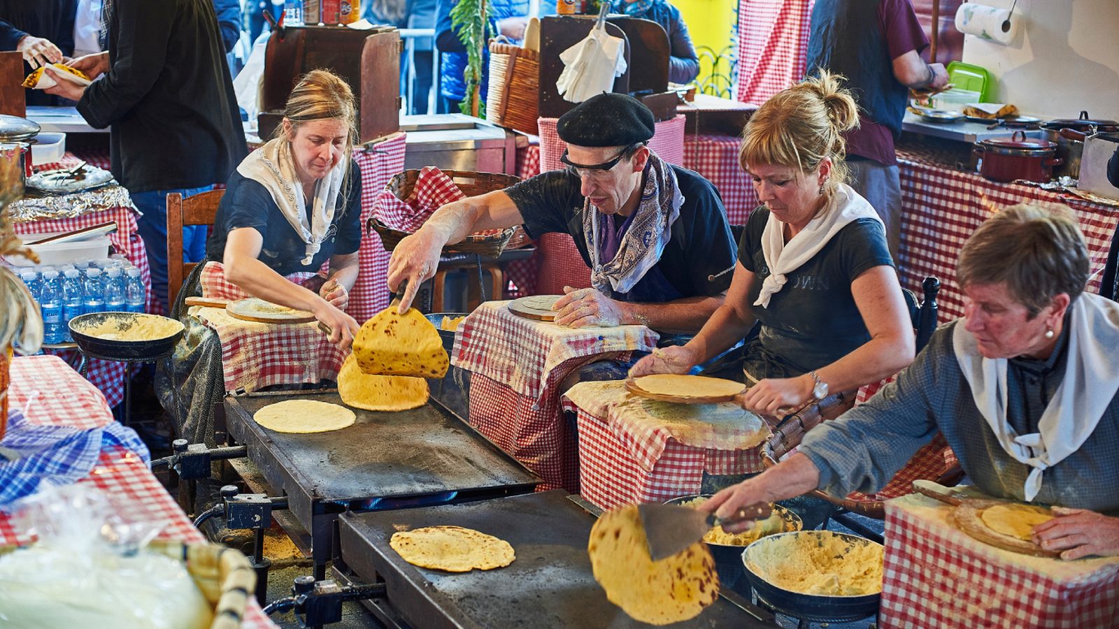 Baserritarras elaborando talos a la plancha durante el Día de Santo Tomás, una tradición que reúne a productores y visitantes en plena ciudad.