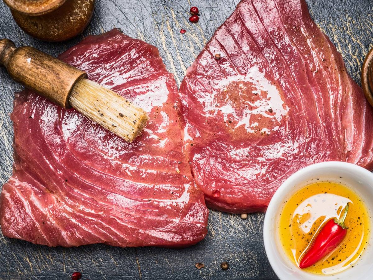 Atún rojo crudo pincelado con aceite especiado, ideal para marinar y preparar al estilo tataki o a la plancha.