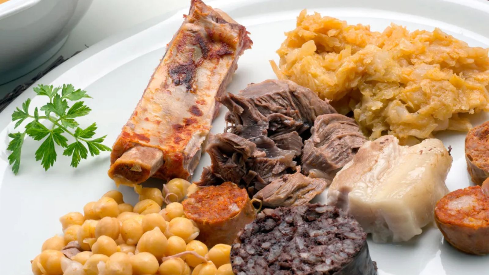 Una versión clásica del cocido lebaniego con su caldo, carnes y embutidos, símbolo de la cocina de montaña que acompaña la Fiesta del Orujo en Potes.