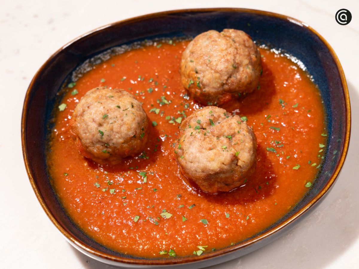 Albóndigas recién servidas sobre una base de salsa de tomate caliente, listas para llevar a la mesa.