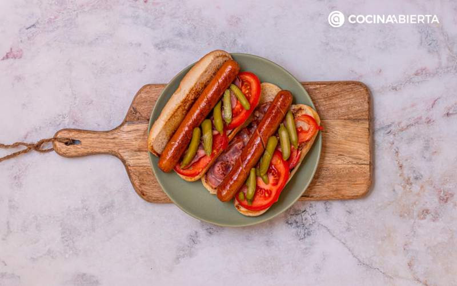 Pon la salchicha, el tomate, el bacon y los pepinillos en el bollo