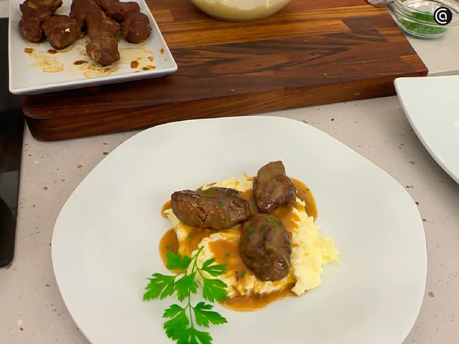 Coloca una base de puré de patatas y pon encima las carrilleras con un poco de salsa