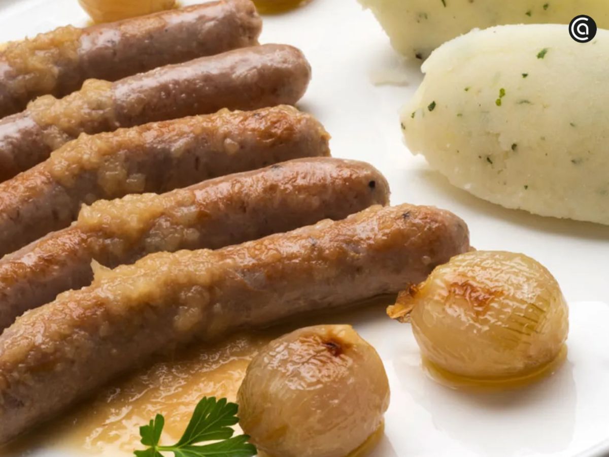Salchichas frescas guisadas en cerveza con chalotas y puré de patatas.