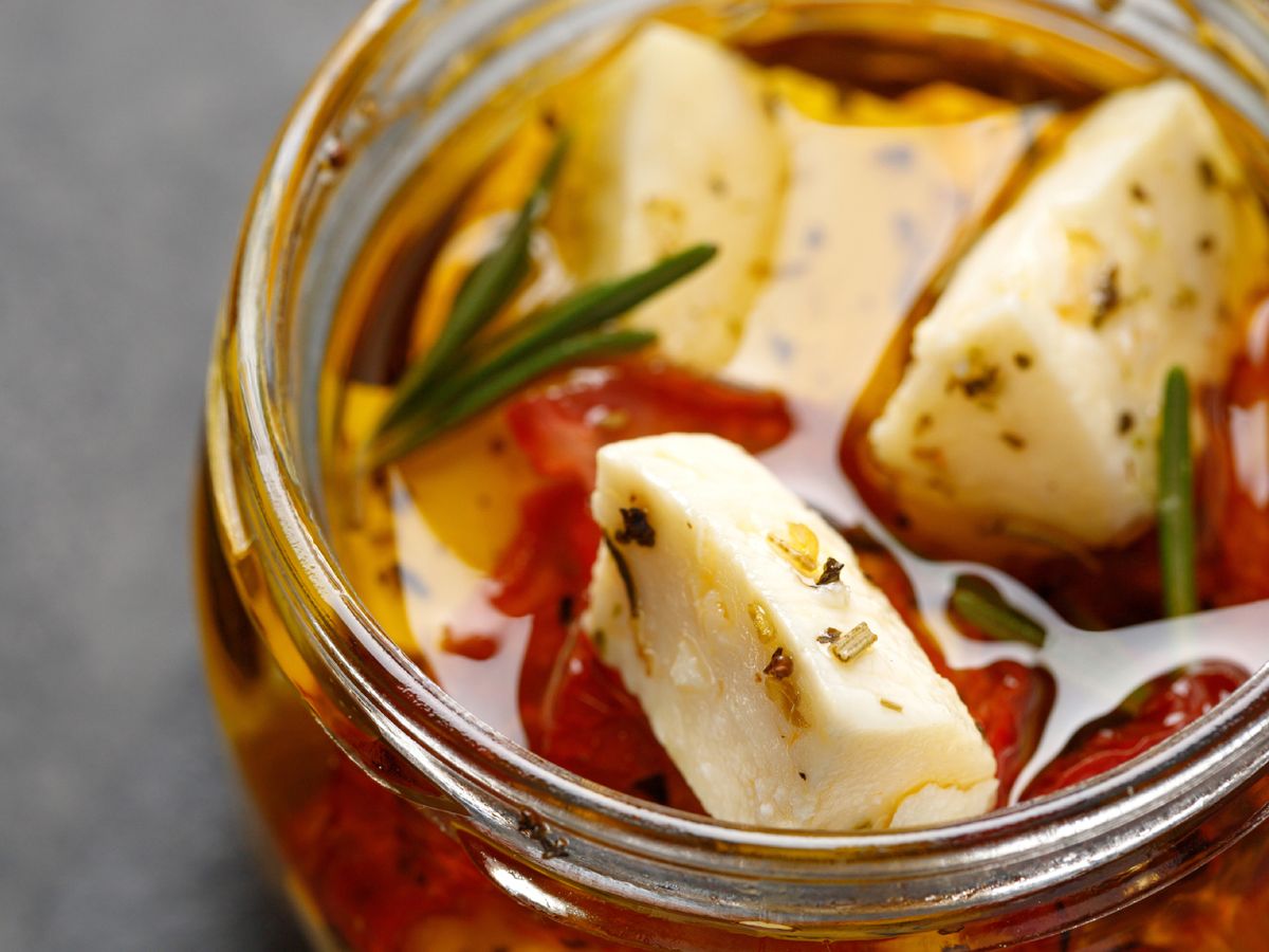 Añadir hierbas o especias al aceite es una forma discreta de aromatizar el queso mientras se conserva.