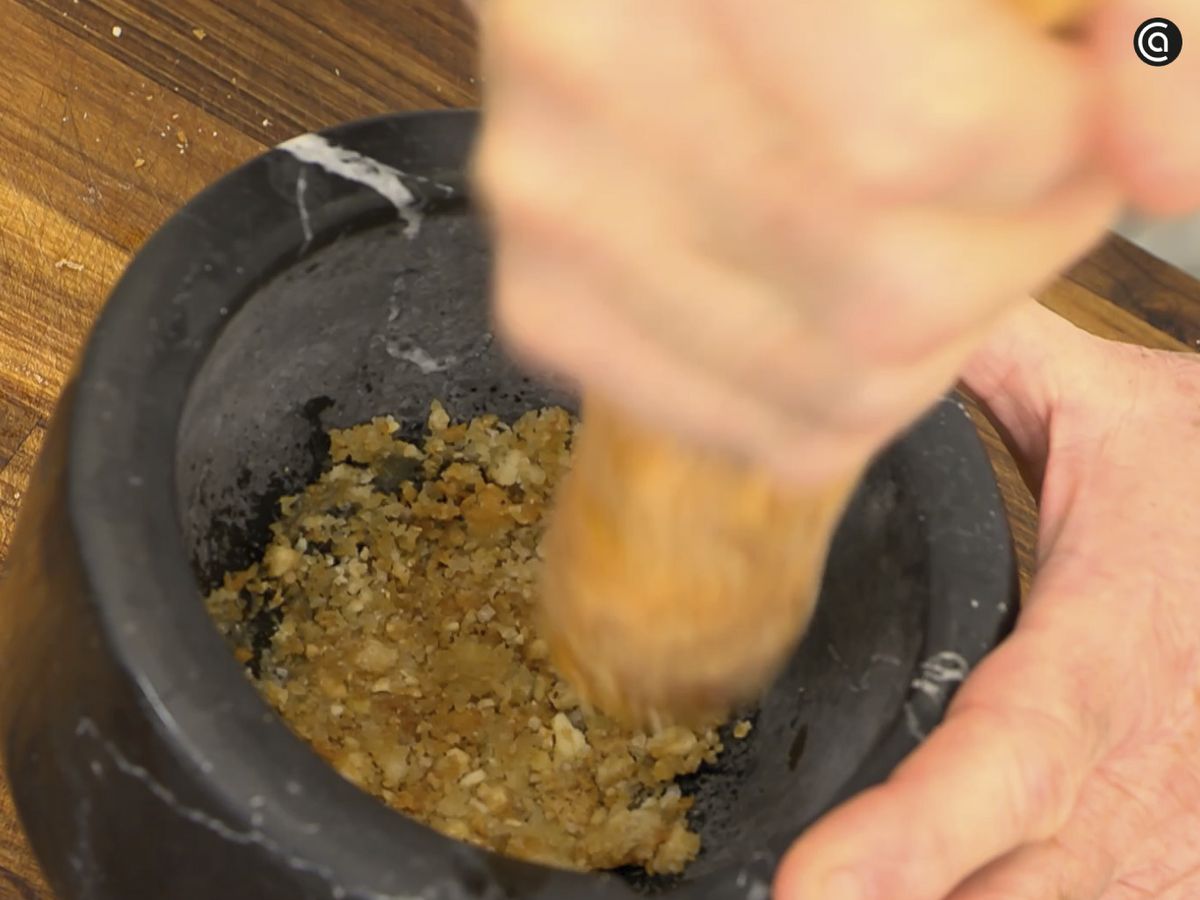 Machaca en el mortero el pan junto con las almendras y las avellanas