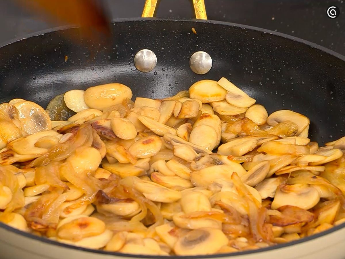 Cocina en la sartén cebolla en juliana y champiñones laminados