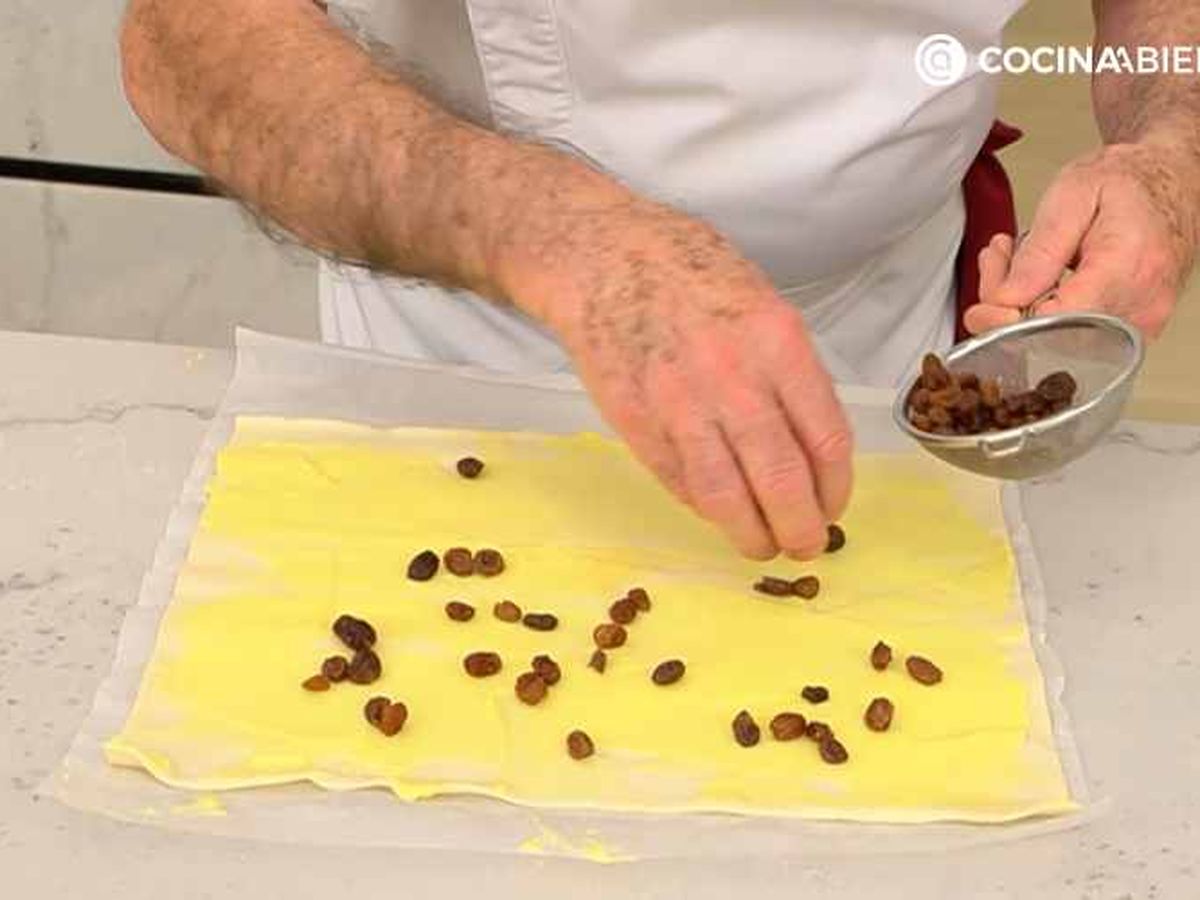 Cubre la lámina de hojaldre con crema pastelera y pasas