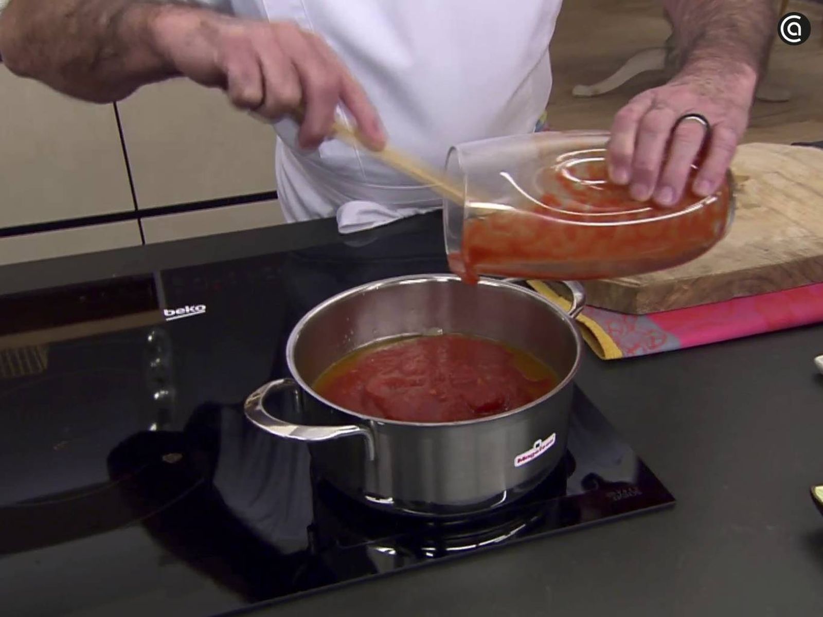 El tomate triturado se incorpora a la cebolla pochada para preparar la salsa.