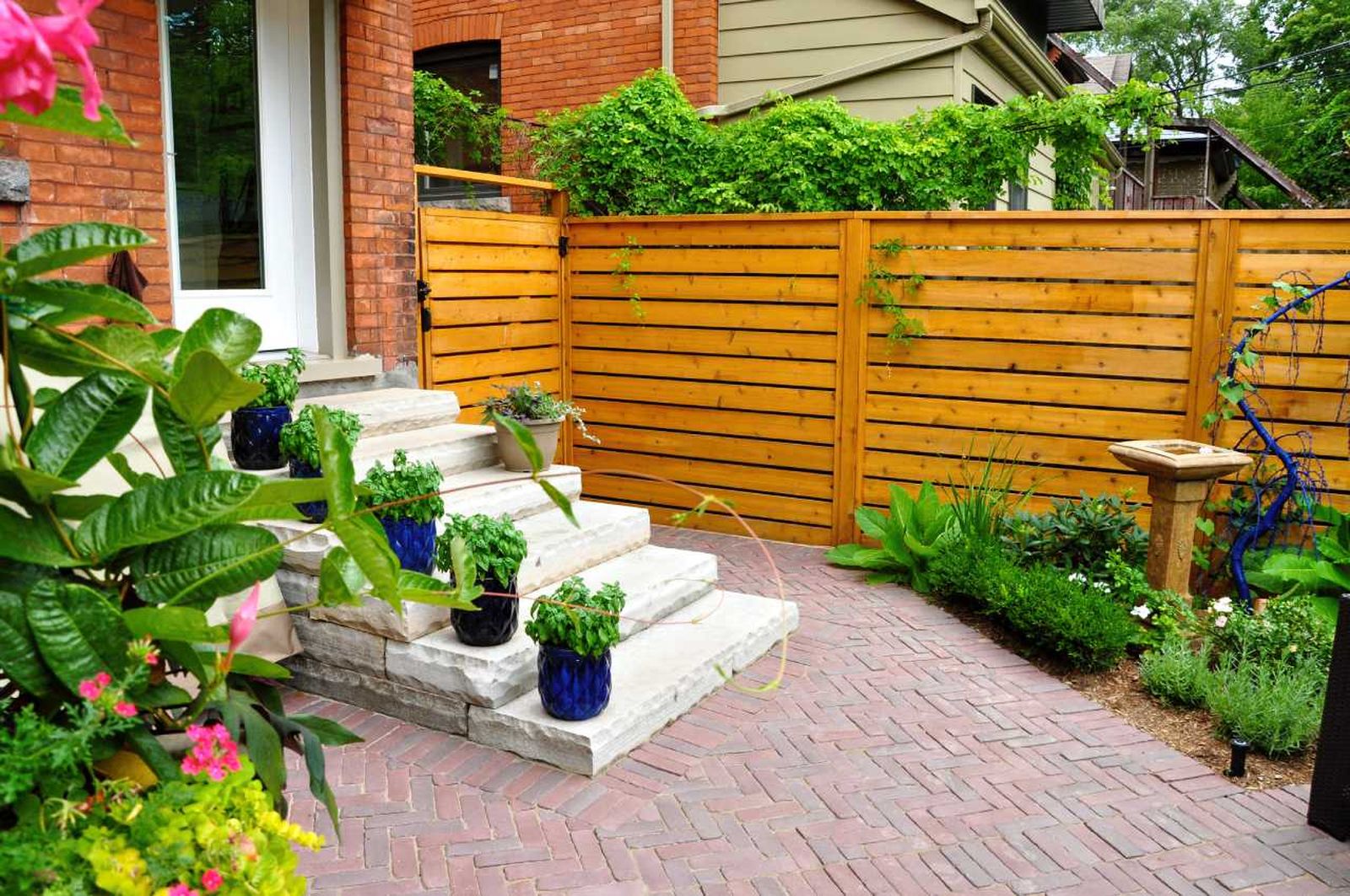 Jardín delantero pequeño con revestimiento de madera decorado con plantas y flores.