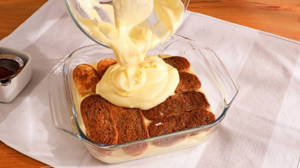 Alterna capas de bizcochos y crema de mascarpone, espolvoreando cacao al final para un toque irresistible