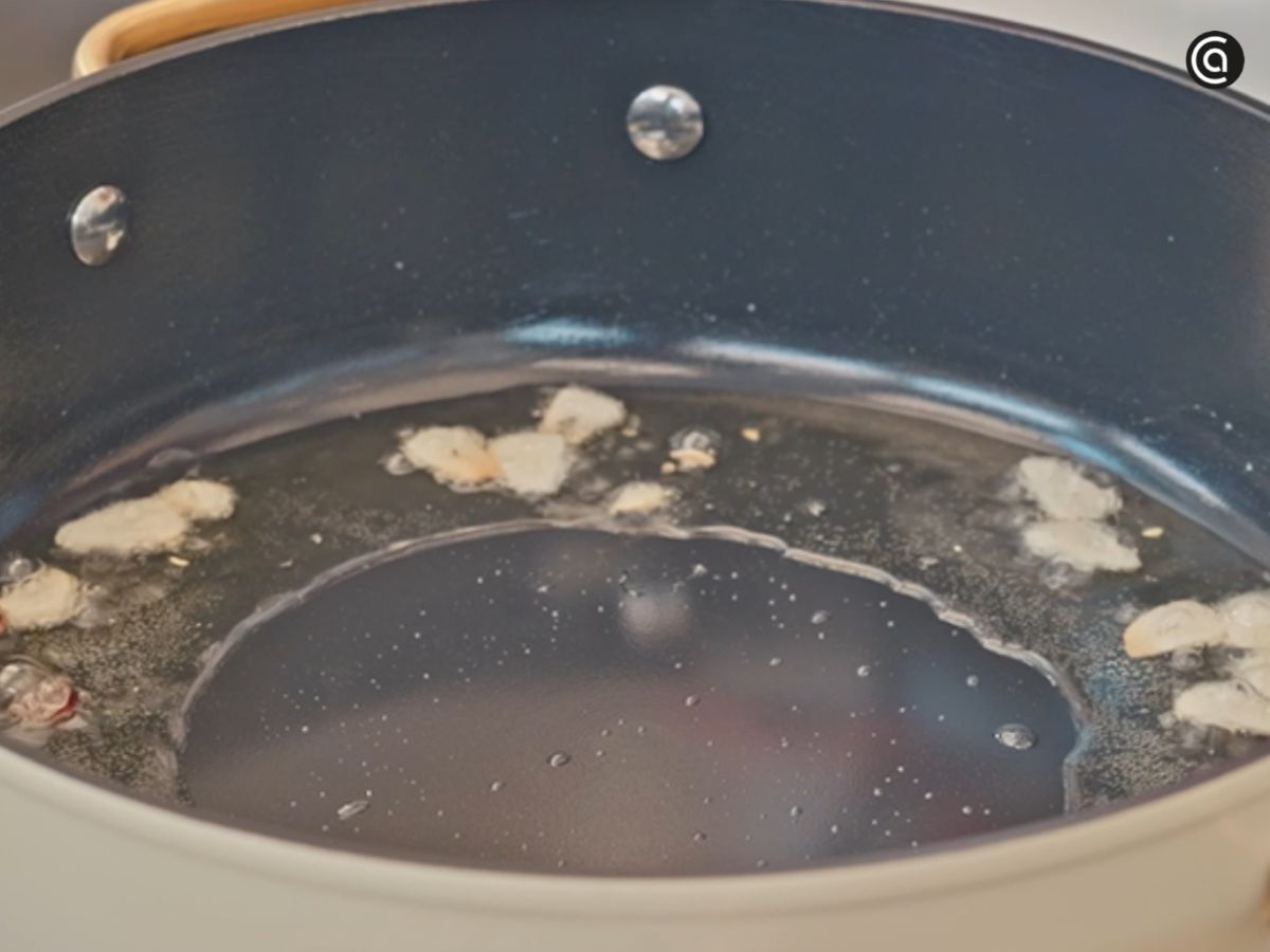 Dora ligeramente los ajos en una cazuela amplia con aceite de oliva para aromatizar la base del guiso.