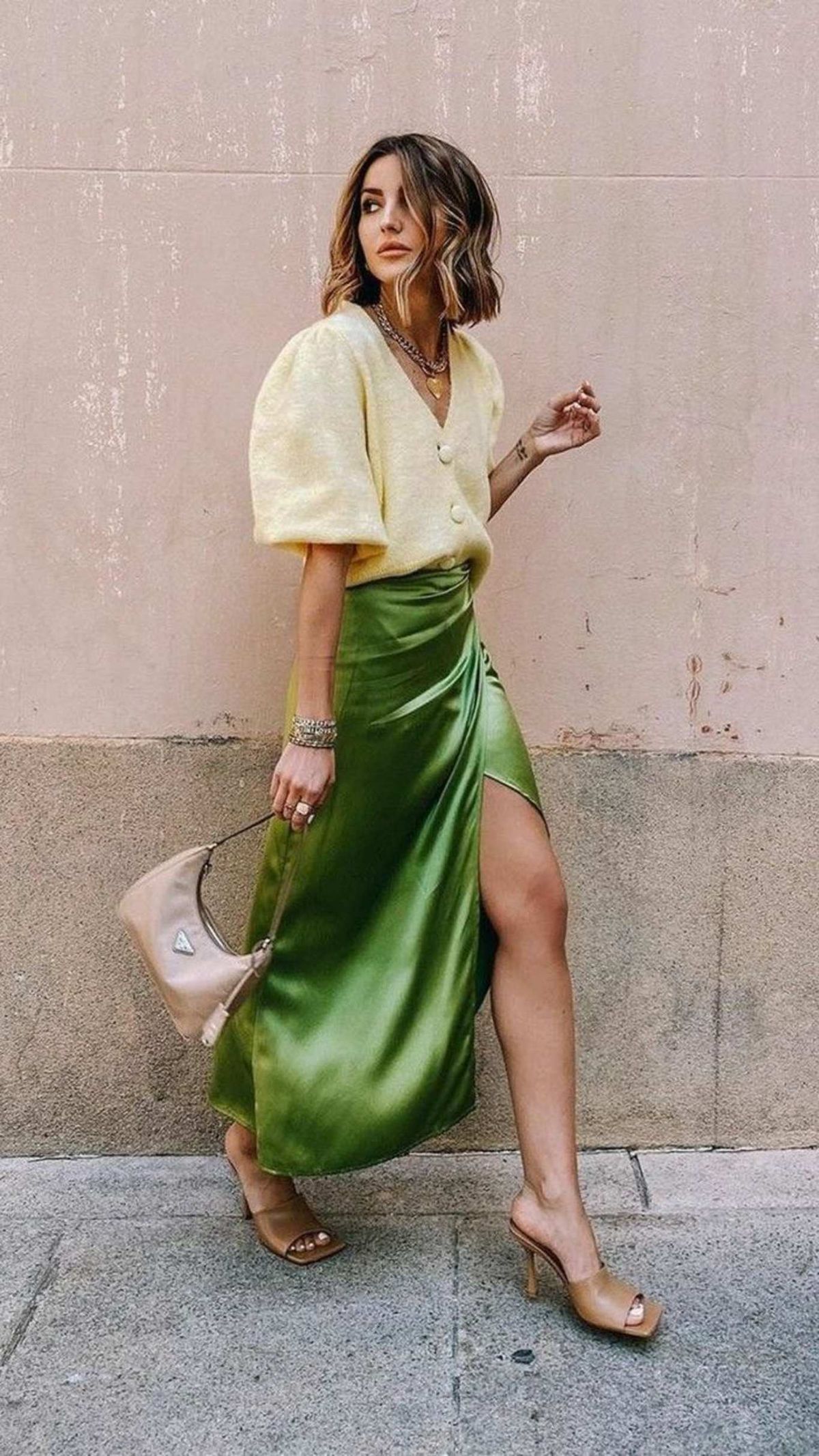 Falda satinada verde con suéter y tacones.
