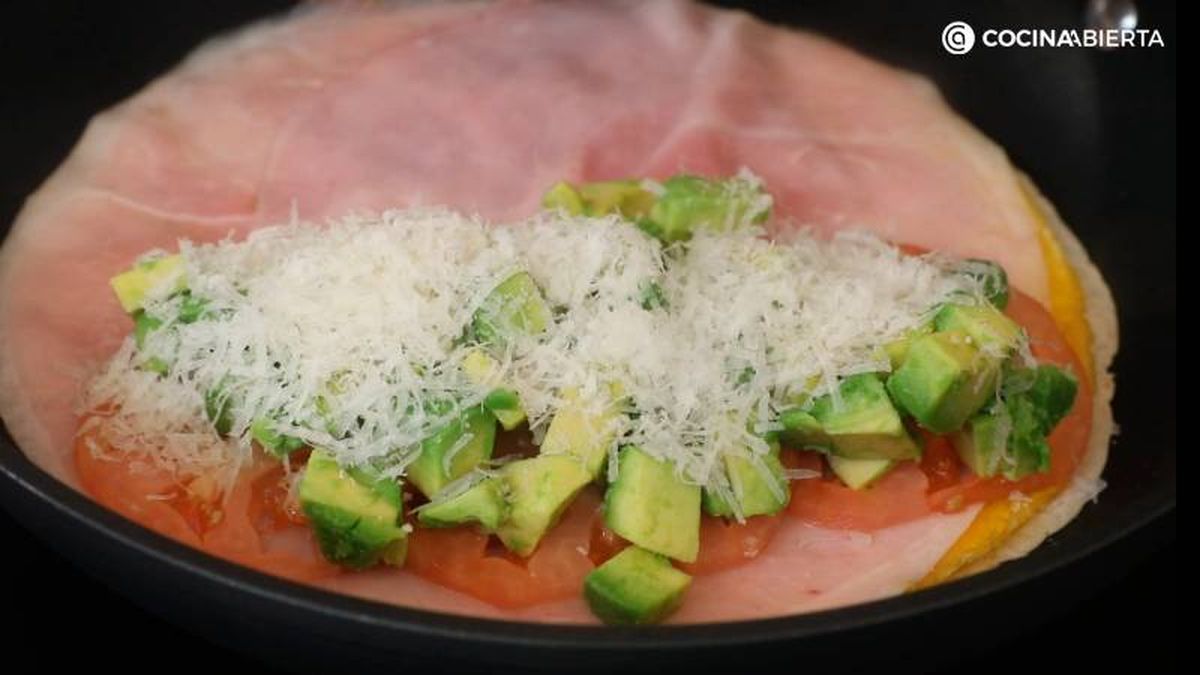 Cubre la tortita de trigo con tortilla, jamón, tomate, aguacate y queso rallado