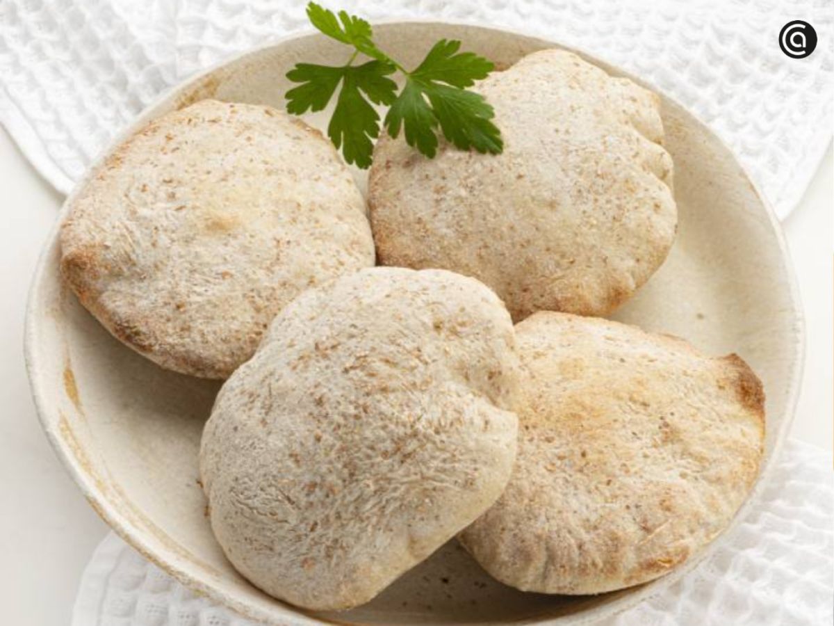 Pan de pita casero recién horneado, con su característica forma inflada y corteza suave, listo para rellenar o acompañar con salsas.