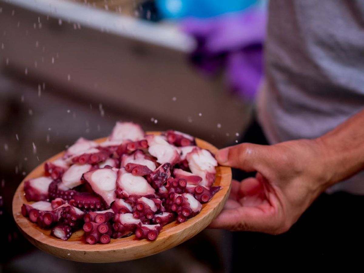 Pulpo recién cocido listo para aliñar con sal, pimentón y aceite de oliva.