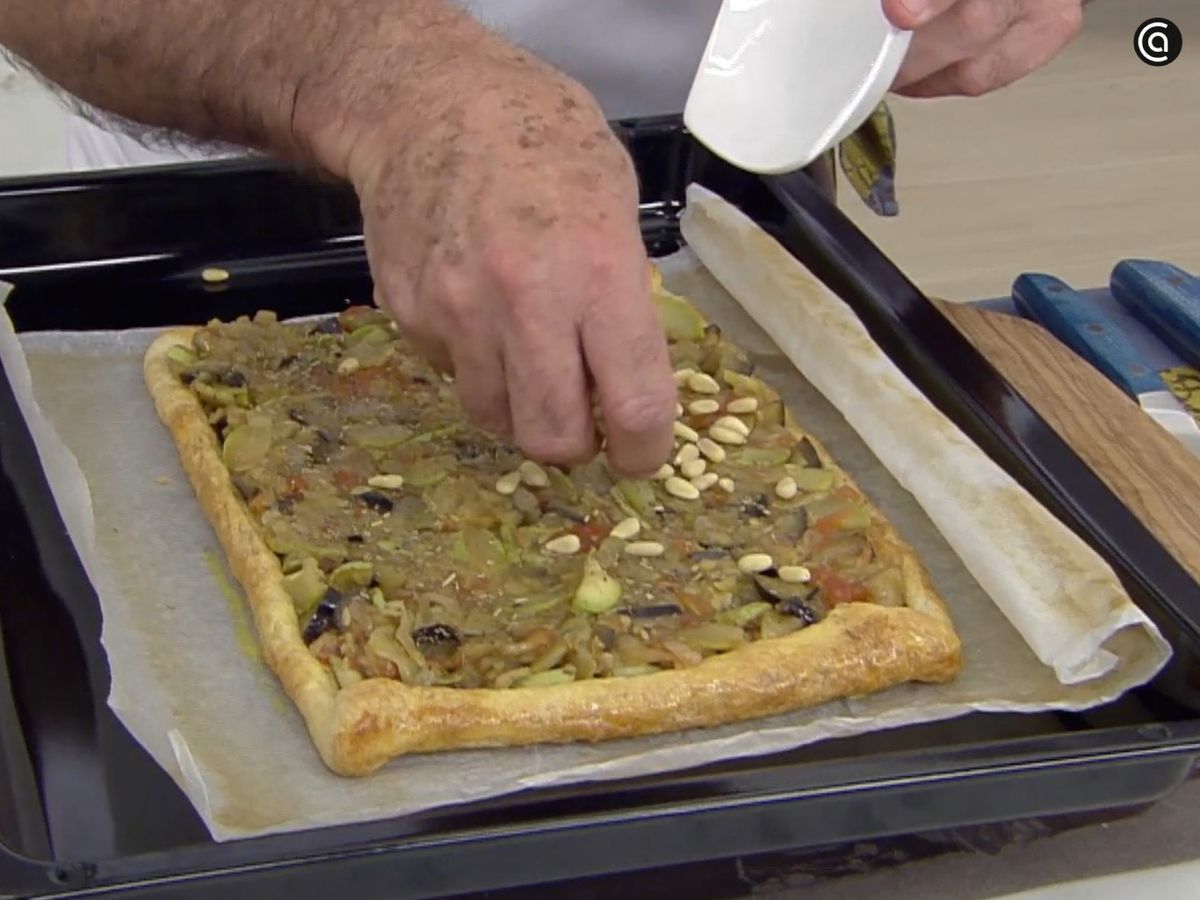 Reparte las verduras sobre el hojaldre y añade las hierbas aromáticas y los piñones