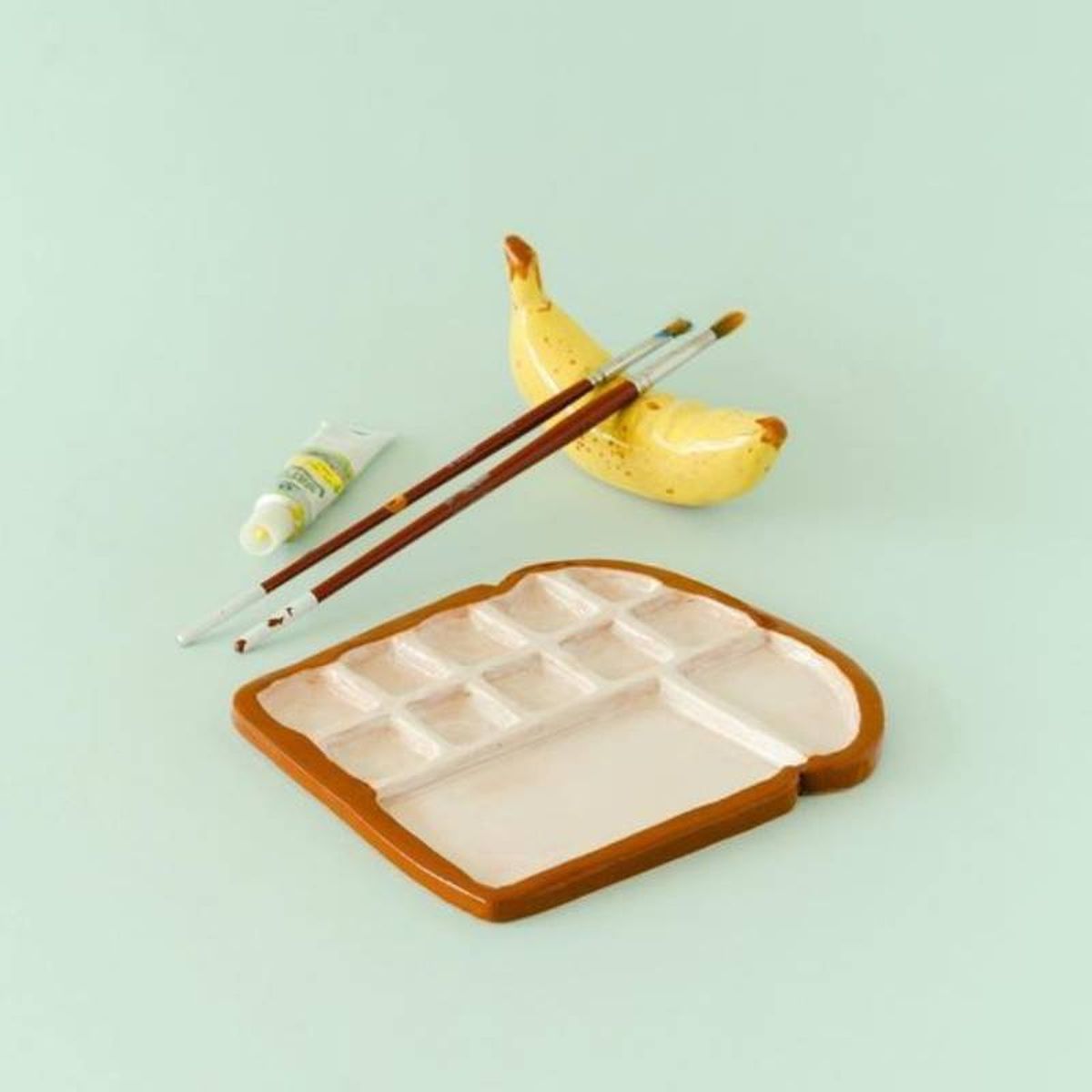 Plátano de arcilla para dejar los pinceles y paleta tostada.