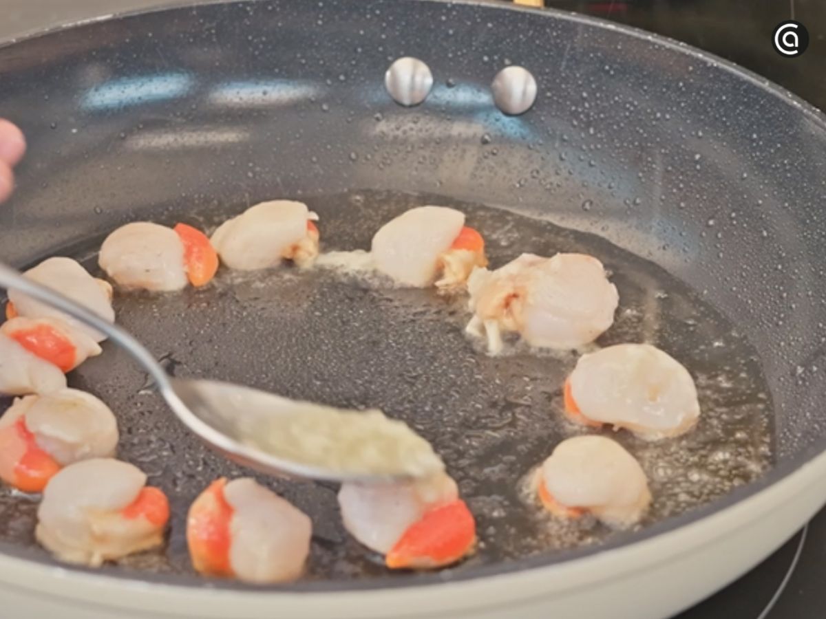 Reparte el aliño de ajo por encima de las zamburiñas mientras se cocinan.