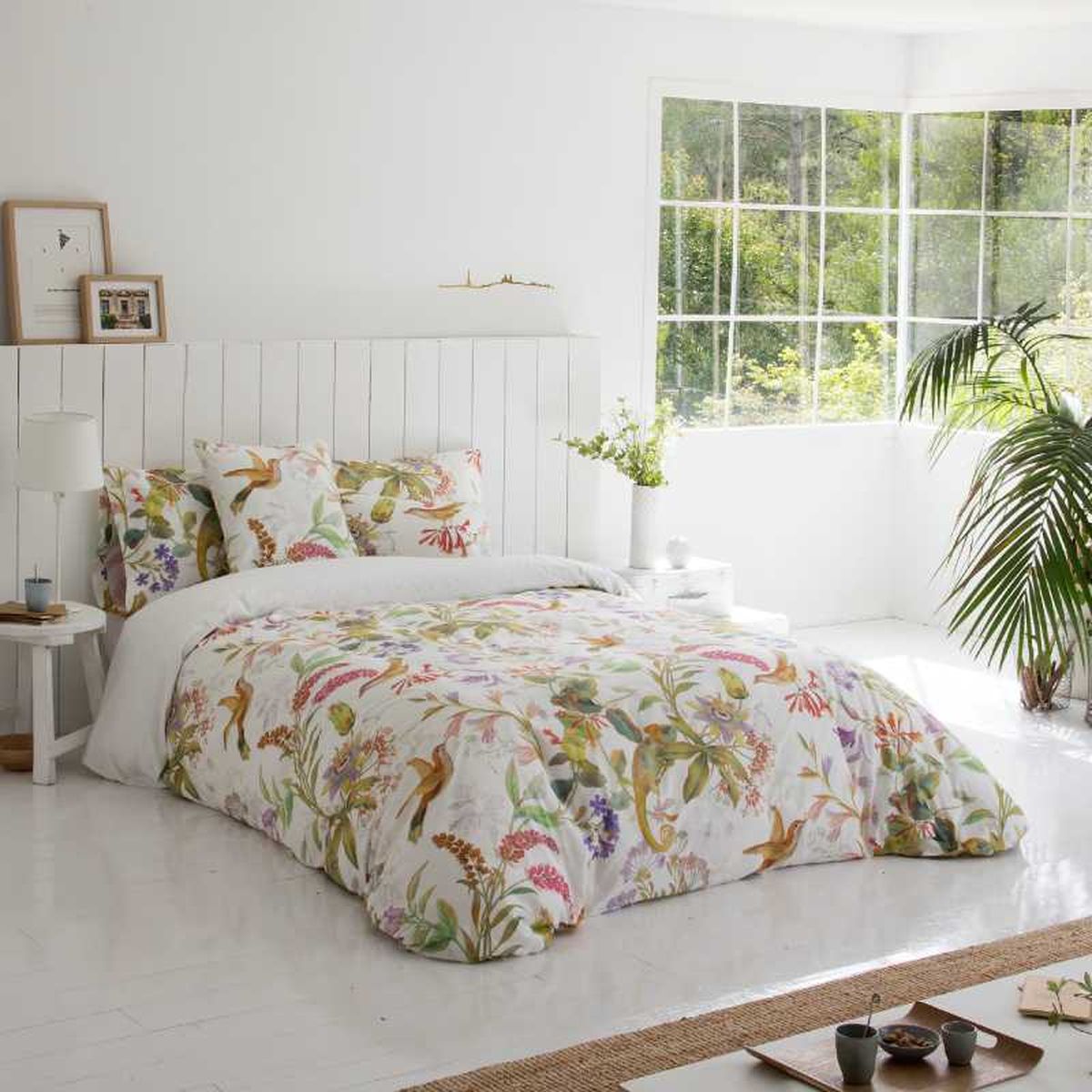 Dormitorio con cama con colcha floral.