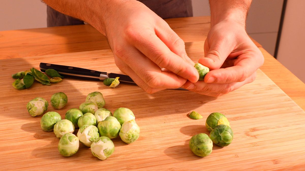 Retira las hojas exteriores y realiza un corte en cruz en la base para asegurar una cocción uniforme