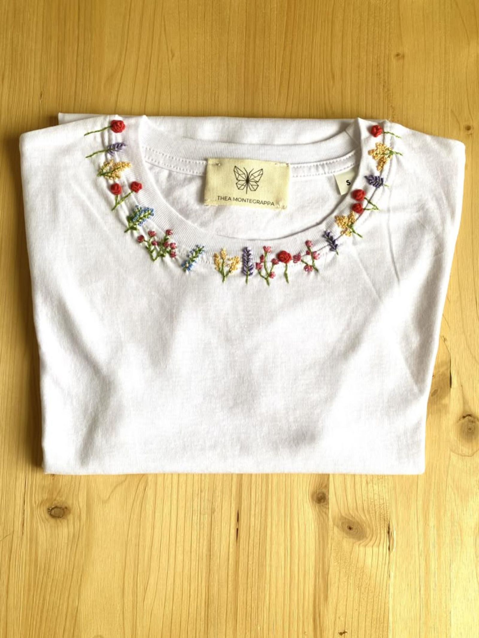 Camiseta con bordado de flores en el cuello.