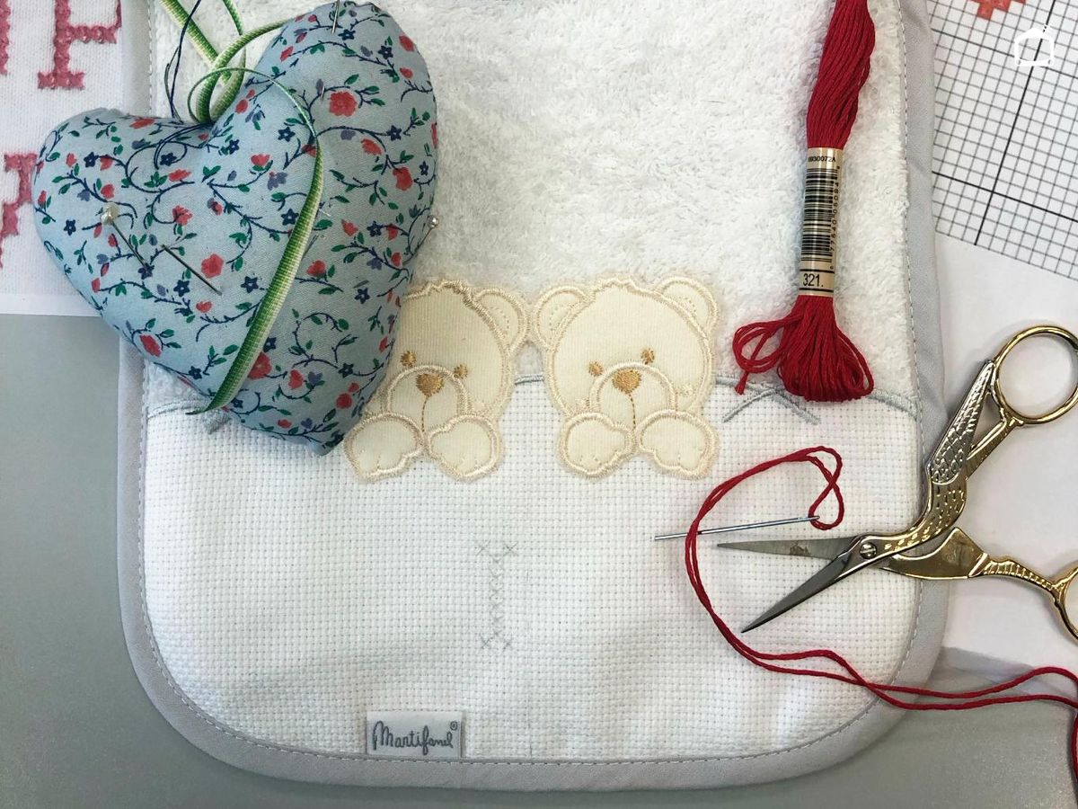 Materiales para bordar un babero con punto de cruz.