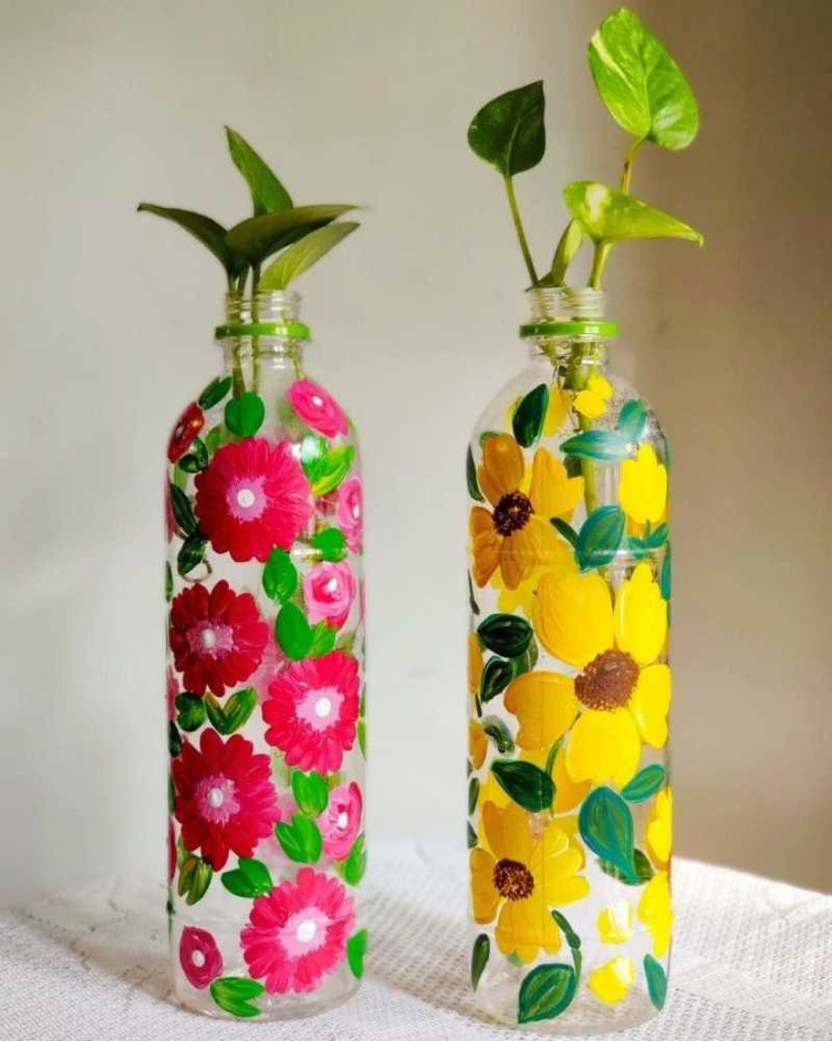 Floreros con flores pintadas hechos con botellas de plástico.