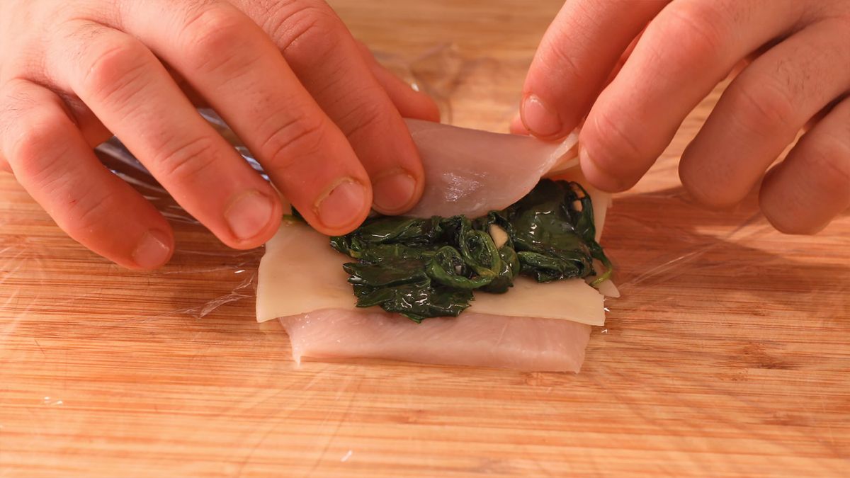 Coloca queso y espinacas salteadas sobre la pechuga de pollo, luego enróllala para crear unos deliciosos rollitos