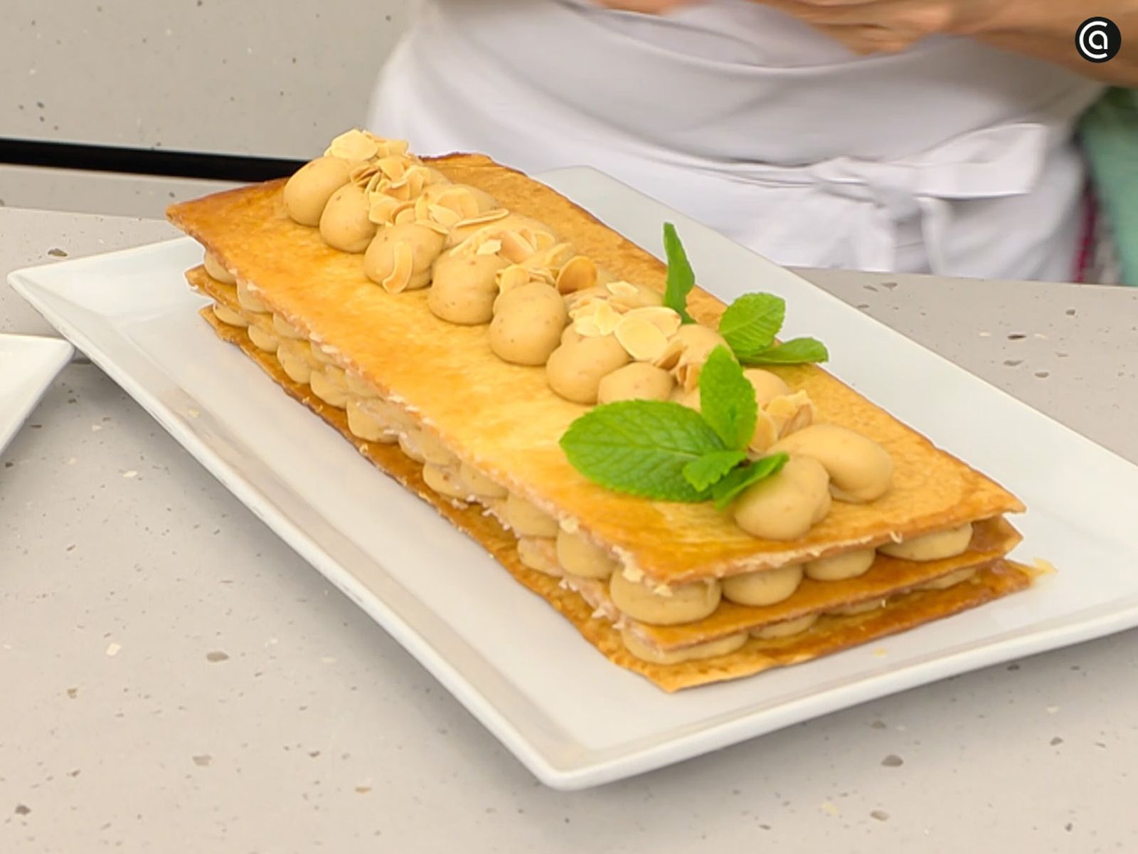 Corona el milhojas de turrón con almendras tostadas y hojas de menta