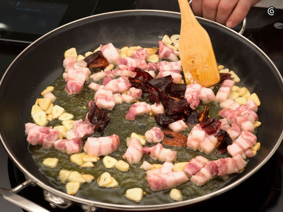 Fríe con un buen chorro de aceite el ajo, la panceta y el pimiento choricero