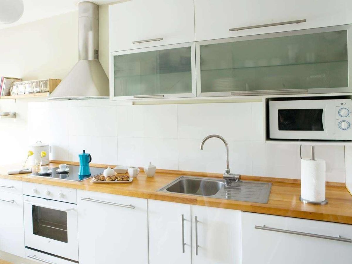 Microondas suspendido debajo de los muebles altos de la cocina.